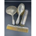 A hallmarked silver four piece dressing table set comprising a mirror, comb and two brushes
