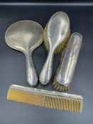 A hallmarked silver four piece dressing table set comprising a mirror, comb and two brushes