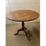 A light oak tilt top table on triform legs