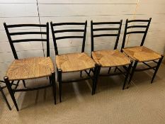 Four ebony chairs with wicker seats and rocket shape legs