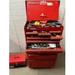 A Snap on Tool box with content, axe and one empty tool box