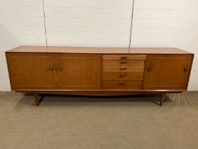A Mid Century teak sideboard with drawers to centre, flanked by cupboards (H73cm W222cm D46cm)