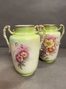 A pair of handpainted twin handle jugs or vases