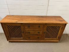 A hardwood sideboard with drawers to centre, flanked by lattice door cupboards (H80cm W179cm D46cm)