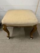 An upholstery stool on gilt legs