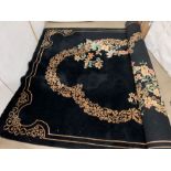 A substantial black ground rug with floral design and gold border (230cm wide)