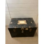 A metal travel trunk with shipping labels.