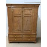 A double antique pine wardrobe with drawers to base (H196cm W153cm D54cm)