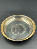 A white metal coin dish with a silver Austrian Maria Theresa Thaler to centre.