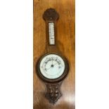 An oak cased barometer with carved leaf detail