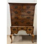 A walnut chest on stand , two short over three long cross banded drawers with shaped apron and