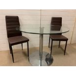 A glass circular dining table and two faux leather chairs