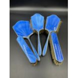 A Five piece silver and blue enamel vanity set to include four brushes and a handheld mirror by