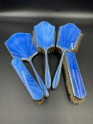 A Five piece silver and blue enamel vanity set to include four brushes and a handheld mirror by