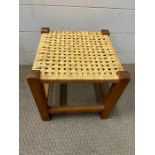 A teak stool with worn seat