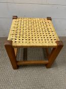 A teak stool with worn seat