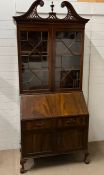 A mahogany bureau cabinet, glazed doors enclosing shelves fall front, opening to fitted interior (