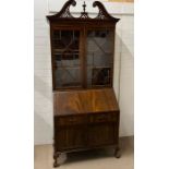 A mahogany bureau cabinet, glazed doors enclosing shelves fall front, opening to fitted interior (