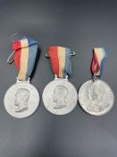 Two Empire Day aluminium medals and a King George V and Queen Mary silver jubilee medal.