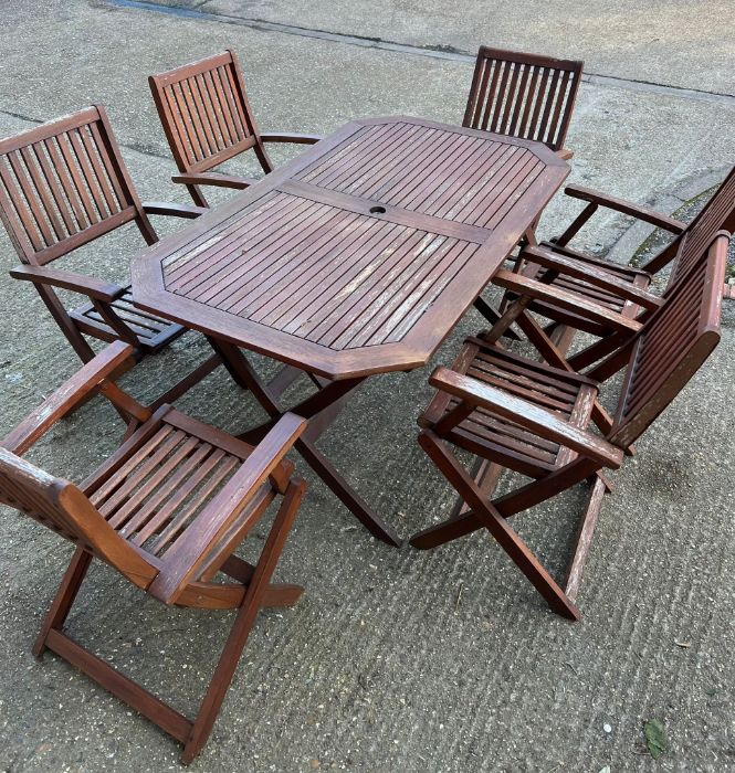 A six seater wooden garden table with folding chairs (H74cm W150cm D87cm)