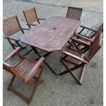 A six seater wooden garden table with folding chairs (H74cm W150cm D87cm)