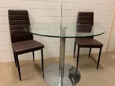 A glass circular dining table and two faux leather chairs