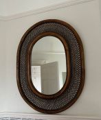 A cane and wicker oval wall mirror