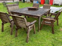 A large wooden slatted square table with four chairs and two seater benches