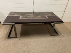 A coffee table with leather and bronze effect, top with geometric design on metal legs