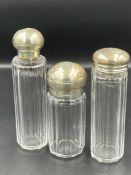 Three silver lidded glass bottles