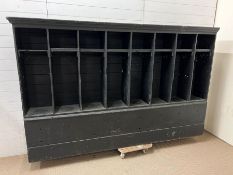 A large wooden school locker/coat wall rack, each pigeon hole has a coat hook and shelf above on a