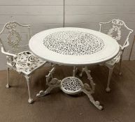 A painted cast iron bistro table and chairs on ball and claw feet