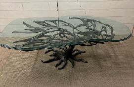 A glass topped coffee table, cast iron base in the form of a tree and its branches supporting the