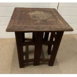 A hardwood folding side table with carved floral decoration