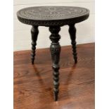 An ebony carved circular table on three turned and carved legs (H50cm Dia38cm)