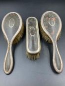 A Hallmarked silver and tortoiseshell dressing table set comprising three brushes.