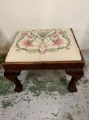 A needlework footstool on ball and claw feet