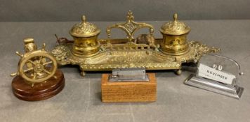 A selection of desk items to include a brass inkwell, ships wheel nut cracker lighter and calendar