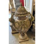 An impressive weathered garden urn with dropped vine and ribbons, finished with nake ladles as