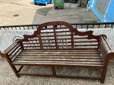 A teak slatted garden Lutyens style bench with scrolled ends and sloping arches