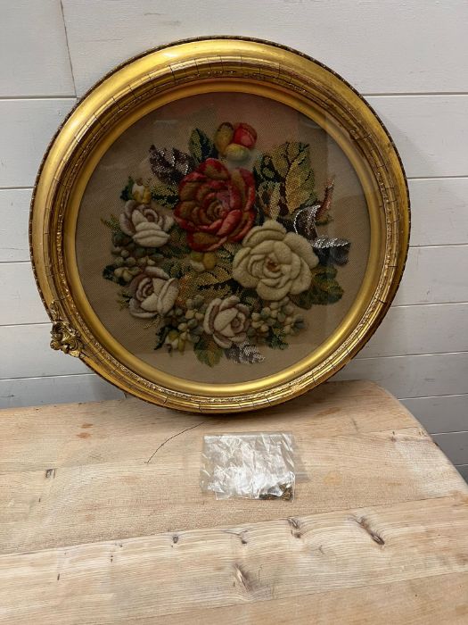 A circular needlework in a gilt frame