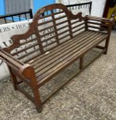 A teak slatted garden Lutyens style bench with scrolled ends and sloping arches