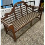 A teak slatted garden Lutyens style bench with scrolled ends and sloping arches