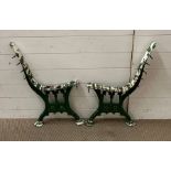 A pair of metal bench ends, painted green in a Gothic style.