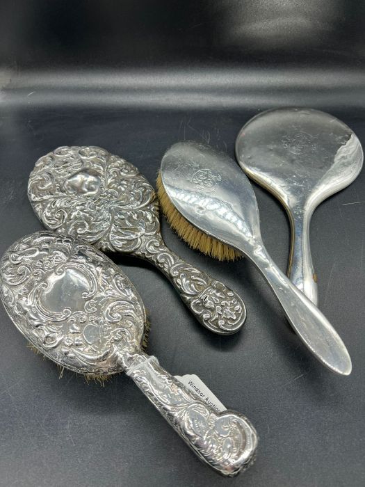 A selection of four silver backed dressing table brushes and mirrors, two of each. (1.155g)