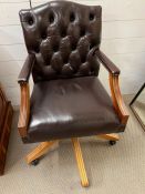 A leather captain style office desk chair with button back and swirl base