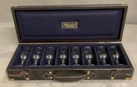 A black leather travelling shooting case with brass fitments of eight drinking glasses by William