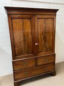 A mahogany linen press with two doors opening up to a hanging rail and three drawer chest under (