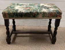 An upholstered footstool on barley twist legs