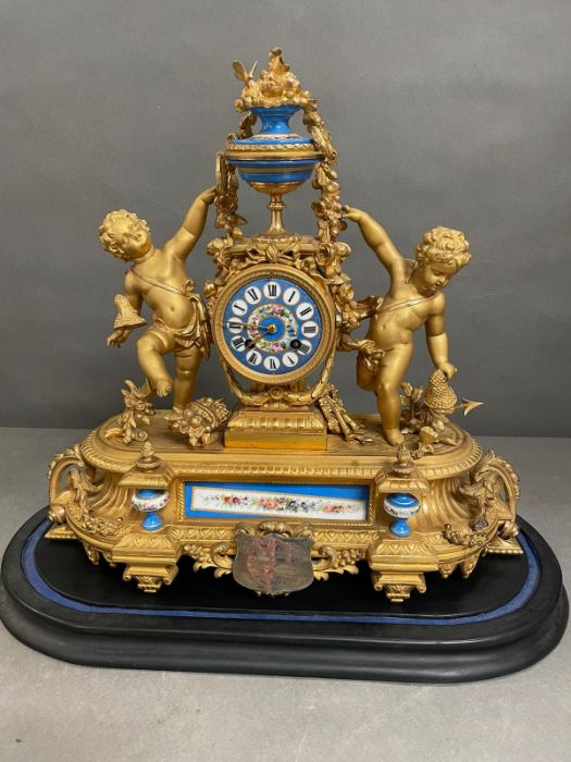 An Eight day Ormolu and enamel eight day clock featuring cherubs and under a glass dome.